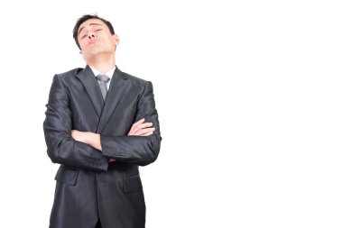 Kendine güvenen, zarif takım elbiseli, koyu renk saçlı genç girişimci kibirli bir yüz ifadesi takınıp stüdyoda beyaz arka planda çapraz kollarla kameraya bakarken kameraya bakıyor.