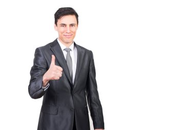 Zarif gri kıyafetli neşeli bir erkek baş parmağını kaldırıyor ve beyaz arka planda tek başına kameraya bakıyor.