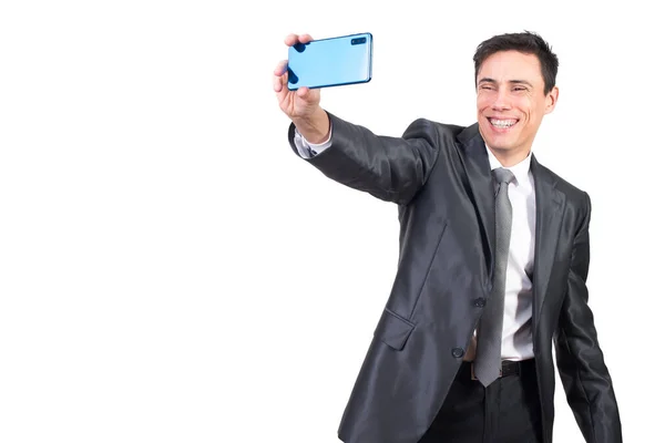 穿着正装的快乐男性一边在现代智能手机上自画像 一边笑着站在工作室的白色背景下 — 图库照片