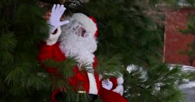 Noel Baba 'da Noel ağacının yanında duran çocuklara kırmızı bir çanta hediye tutuyorum.