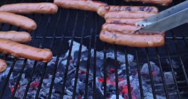 Lezzetli sosisler mangal ateşinde cızırdıyor alevlerin üstünde ızgara yapıyor.