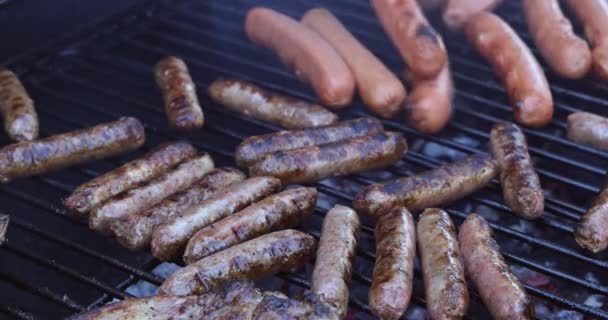 Heerlijke worstjes zinderende over de kolen op barbecue grill — Stockvideo