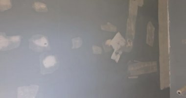 Uzun saplı fırça, duvarda beyaz astar boya uyguluyor.