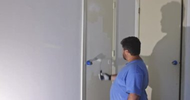 İşçi evi restorasyonu. Eldivenli boyalı eller. Kapıyı elle boyuyor.