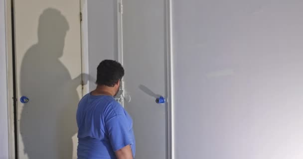 Contractor master processes painting for painting wooden doors with using paintbrush — Stock Video