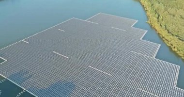 Suyun üzerinde yüzen paneller, güneş ışığının altındaki mavi bir gölette yüzen güneş panelleri.