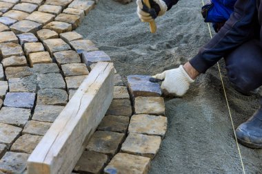 Şehir caddesinde inşaat işçisiyle taş kaldırım döşemek.