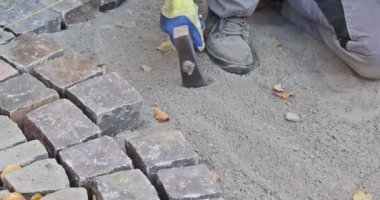 Yol işçisi taş ve çekiç kullanarak taş döşeyen inşaat yolları yapıyor.