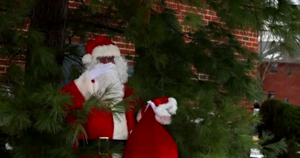 Der Weihnachtsmann steht neben einem Weihnachtsbaum und hält in einer roten Tüte Geschenke für Kinder für Weihnachten im Schnee