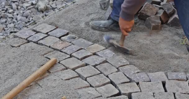 在道路人行道上安装和安放石料的建筑工人的近照 — 图库视频影像