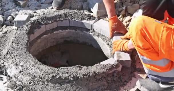 Construcción de alcantarillado con trabajador de servicios públicos instalando alcantarillado subterráneo pozo — Vídeos de Stock