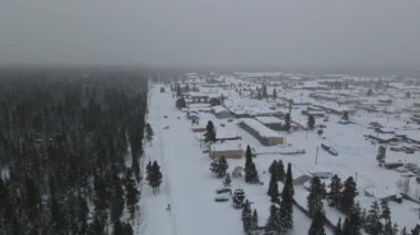 Karlı bir kış günü ormanın yakınındaki küçük bir kasabada yerleşim bölgelerinin hava manzarası.
