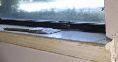 Müteahhit pencereleri beyaz boyayla boyuyor.