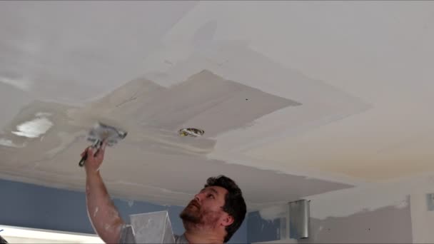 Hombre enyesando el techo con acabado masilla en la habitación con espátula de masilla — Vídeo de stock