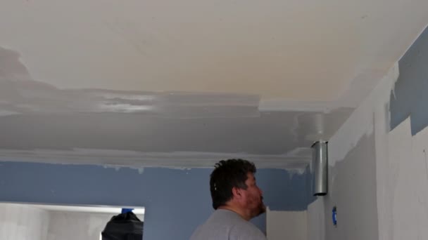 Строитель с лопатой штукатурки потолок в комнате дома — стоковое видео