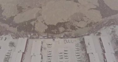 Kar tanelerinin içinde kış yağışı, kar kaplı çatısı ve gri gökyüzü arkaplanı olan evimizde.