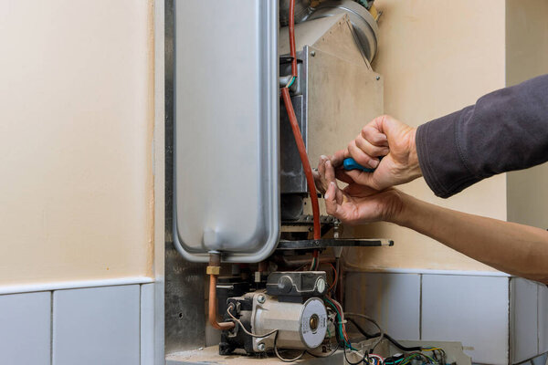 Repairman fixing a gas water heater with setting up servicing repair