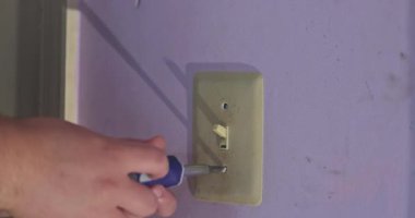 Yeni boya duvarı için hazırlama duvarındaki beyaz ışık düğmesi kapağı plastiği kaldırılıyor