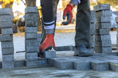 İşçi kaldırıma taş döşeyen bir zanaatkar inşa etmek için tuğla kullanır.