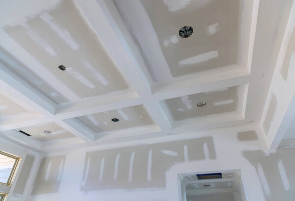 Finishing putty on drywall with a spatula the house on ceiling and wall