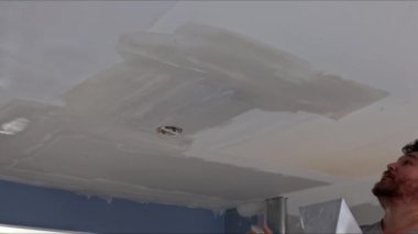 Tavanda oda için macun kaplaması yapan işçi eli.