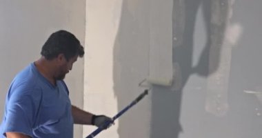 Duvarı boyayan ressamın arka görüntüsü, boya silindiri ile.