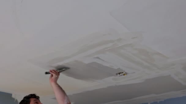 Plasterer lembut langit-langit permukaan dengan pisau putty di pembaharuan rumah — Stok Video