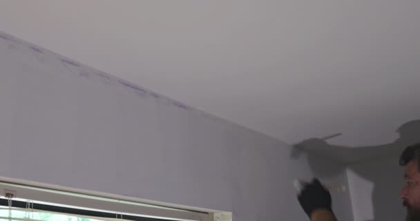Hem renovering tillämpa färg på väggen med hjälp av pensel målare arbetar inomhus — Stockvideo