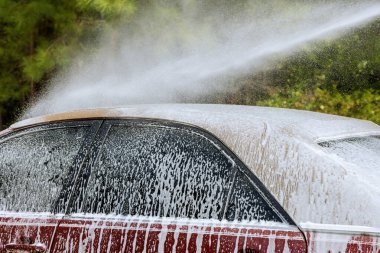 Araba yıkama servisi yüksek basınçlı su jeti kullanıyor.