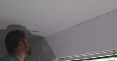 Duvarı boyamak için fırça kullanan profesyonel bir ressam.