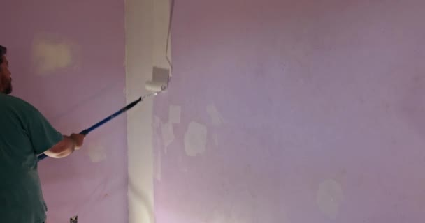 Zadní pohled na malíře, jak maluje stěnu, s válečkem — Stock video