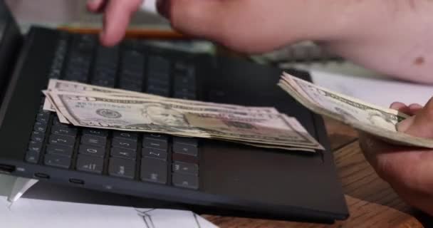 Manos de contador hombre contando billetes de dólar con escribe el resultado a la computadora portátil nota — Vídeos de Stock