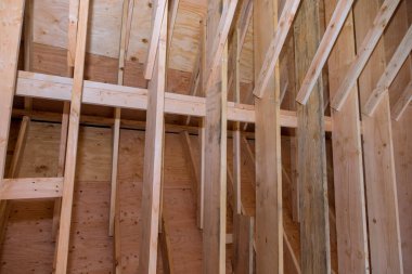 İnşaat kirişleri altında ahşap çerçeveli bir ev evin çatısını döşemiş.