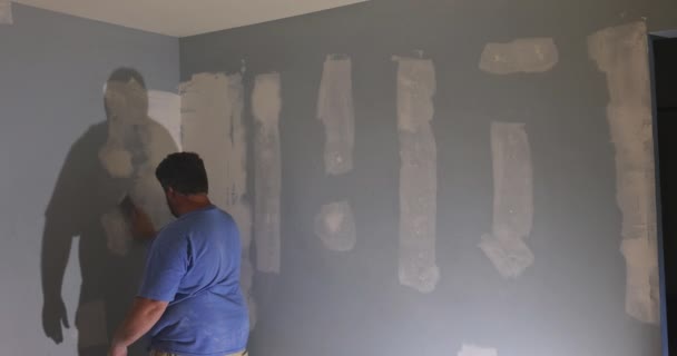 Werknemer schuren van de gipsplaten modder met behulp van zand troffel tijdens de renovatie het huis — Stockvideo