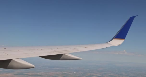 Flygplan flyger ovanför moln i flygplan vinge på blå himmel bakgrund. — Stockvideo