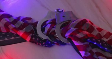 Legal law of handcuffs with the flashing red and blue police lights on American flag background