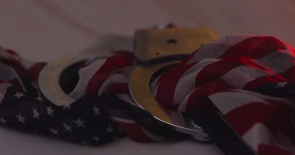 Police at under arrest of handcuffs police with the flashing red and blue police lights on American flag background — Wideo stockowe