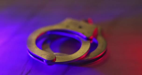 चमकती लाल और नीले पुलिस लाइट्स के साथ हथकड़ी का कानूनी कानून — स्टॉक वीडियो
