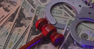 Wooden judge gavel with handcuffs US dollar bills in light flashes police