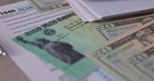 1040 Forma fiscale con assegno di rimborso e valuta Banconote in dollari USA primo piano — Video Stock