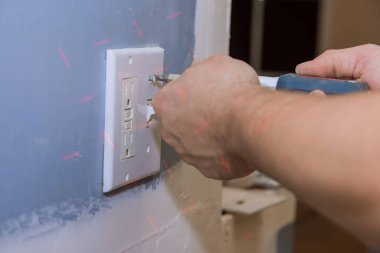 Yeni boya duvarı için hazırlama duvarındaki beyaz ışık düğmesi kapağı plastiği kaldırılıyor.