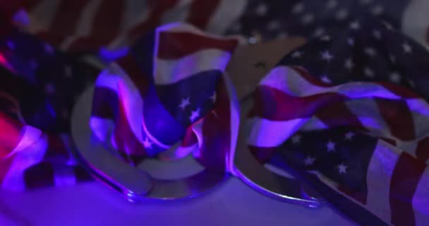 Flashing red and blue police lights of handcuffs police with legal law arrest in American flag background — Stock video