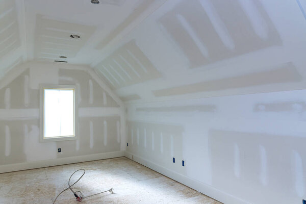 Finishing plastering drywall in ready for paint with new house under construction
