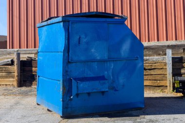 There are garbage bags in the metal container with rubbish