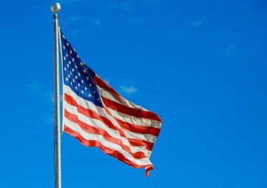 American national flag waving the among against a blue sky