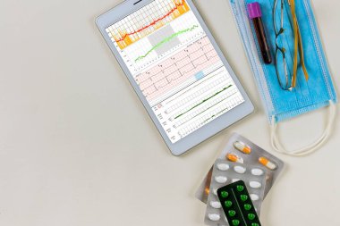 Dijital tablet ve haplarda kalp elektrokardiyogramı olan bir kardiyoloji hastasının sağlık raporu.