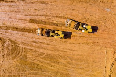 Ağır traktör makinelerinin toprak taşıdığı yeni bir inşaat alanı için arazinin hava manzarası hazırlığı