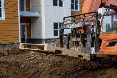 Çalışan bir inşaat alanında ahşap paletle hareket eden bir yük kamyonu.