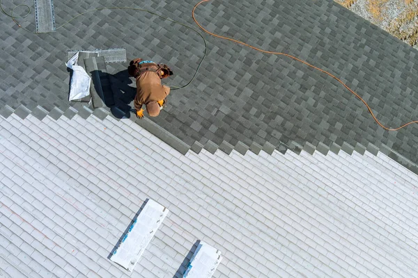一个工人用空气锤和钉子在房顶上装弹子 — 图库照片