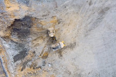 Kazıcı, granit ocağındaki kamyona taş yüklerken iş başında.